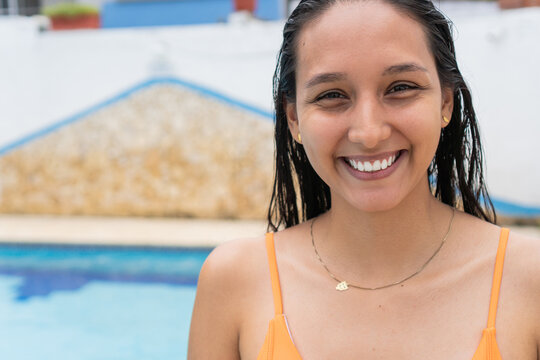 Latin woman in front of swimming pool on a sunny day.