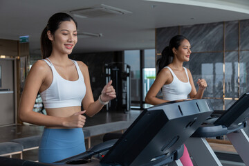 Obraz premium Sporty asia woman exercising on multistation at gym for arm and shoulders muscles. Fitness exercising in gym at condo 