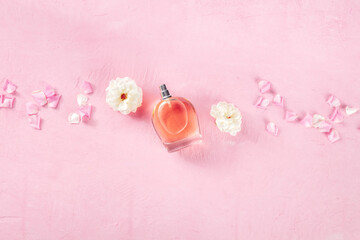 Rose fragrance essence flat lay composition, shot from the top on a pink background with fresh flowers and copy space, organic floral perfume concept
