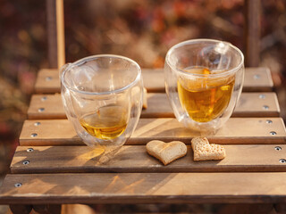 Drinking tea with cookies on wooden table. Cozy autumn mood scene in autumn park