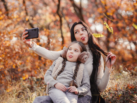 Fashionable mother with daughter. Family in a autumn park.
