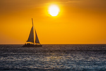 Fototapeta na wymiar Idyllic beach with sailboat in Aruba at golden sunset, Dutch Antilles
