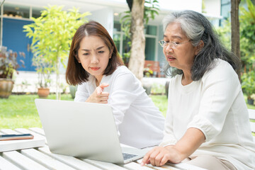 Asian daughter teaching old elderly woman use online Social media in computer laptop after retirement. Concept of Learning technology and adaptation of the elderly