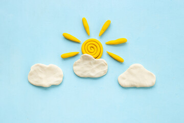 Fototapeta na wymiar Weather forecast concept with plasticine sun and clouds, top view