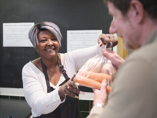Volunteer giving man vegetables in community food center