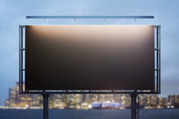 Obraz premium Blank black billboard on cityscape background at evening, front view. Mock up, advertising concept