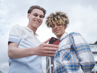 Smiling male couple using smart phone