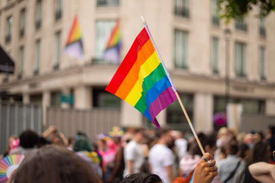 People taking part in LGBT parade, person holding rainbow flag