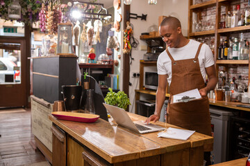 UK, London, Cafe owner using laptop at counter © Cultura Creative