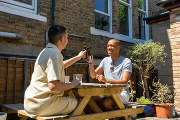 UK, London, Smiling gay couple toasting with beer in rooftop garden