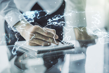 Double exposure of abstract digital world map and man hand writing in notebook on background, research and strategy concept