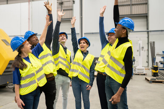 group multiracial engineers men and women, high five hands in factory, celebrating holiday.