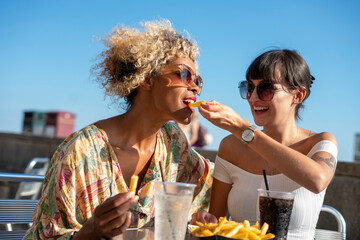 Female couple eating french fries in outdoor restaurant