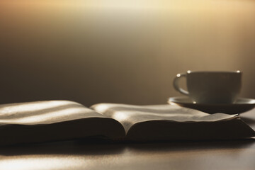 Open the Bible in the morning for prayer with a cup of coffee on a wooden table.  with the morning...