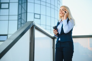 Business Woman With Phone Near Office. Portrait Of Beautiful Smiling Female In Fashion Office Clothes Talking On Phone While Standing Outdoors. Phone Communication. High Quality Image.