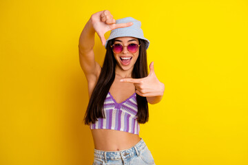 Photo of young excited cheerful lady enjoying summer party holiday take picture with hands isolated on yellow color background