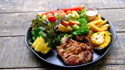 Grilled steaks pork with  mixed fruit  and green salad.
