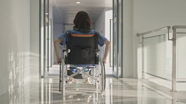 Rear view of a woman in wheelchair in hospital hallway,Slow motion