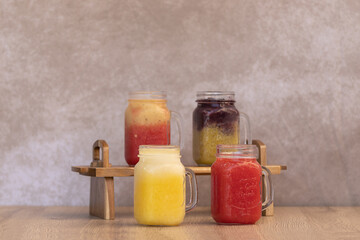 cold fruit juices or ice cream in glass jars. four types of juices of different colours and...