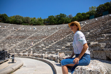 Tourist in Greece. A European woman in profile with a hat and sunglasses visits the theater of Epidaurus in the Peloponnese. Greece, July 2022.
