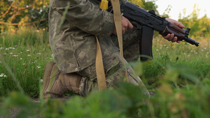 a Ukrainian soldier in camouflage holds a machine gun in a combat position. an infantryman at a...