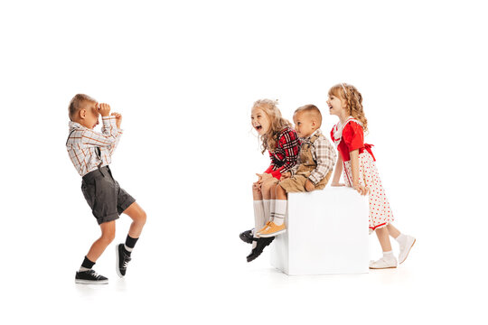 Portrait of little stylish children, boy taking photo with retro camera of laughing kids isolated over white studio background