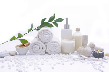 Obraz na płótnie Canvas Spa setting with bottles of essential oil , herbal ball, salt in bowl ,candle , herbal ,ball, eucalyptus leaves, on pile of white stones