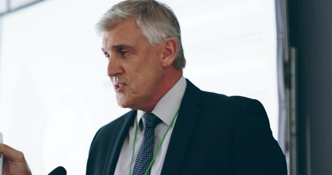 A mature, confident and professional business man giving a presentation at a conference. A well established senior corporate executive sharing his knowledge and expertise to his fellow colleagues.