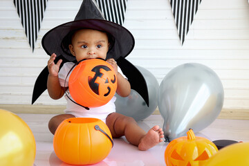 Adorable African baby kid dressing up in vampire fancy Halloween costume with black bat wings,...