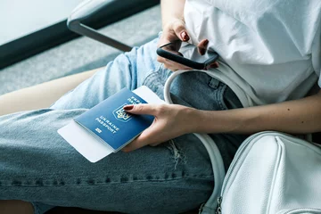Biometric Ukrainian passport in female hands at the airport. Citizen of Ukraine is forced to leave her home because of the war with Russia. Ukrainian refugees immigrants abroad. © domarevatanya