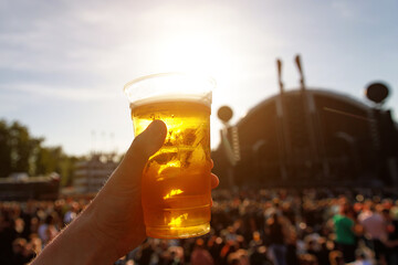 Disposable beer glass in man's hand at a summer music festival.