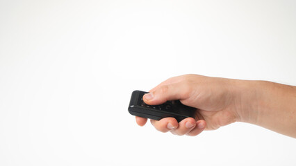 A man's hand holds a small remote control on a white background