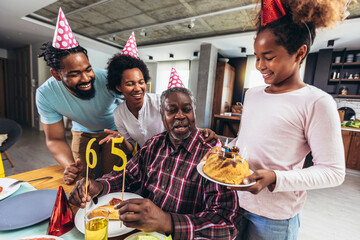 Multi-Generation african american family celebrating grandfathers birthday at home together - Powered by Adobe