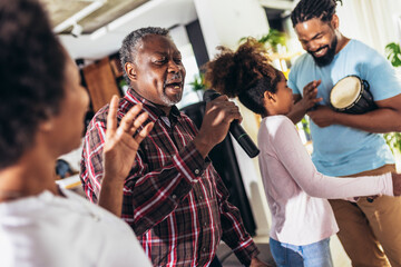 Family singing karaoke with microphones at home
