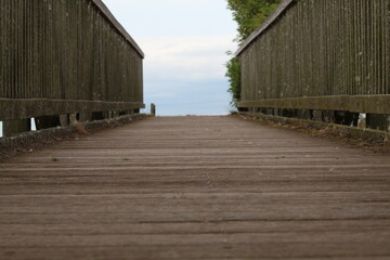 Fototapeta premium A wooden bridge crossing over a river at a nature reserve. This is an old structure which is crossed many times a day by tourists. Below are ducks and swans.