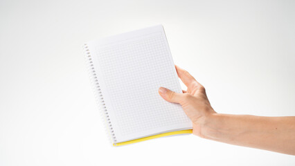 A woman's right hand holds a notebook in a cage on a white background space for inscription