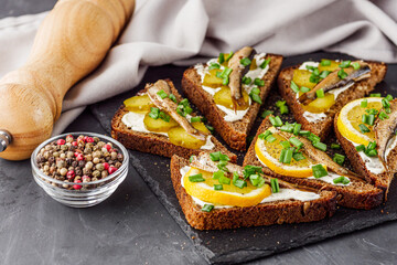 canapes with sprats on a black stone tray