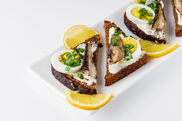 canapes with sprats on a white rustic wooden background