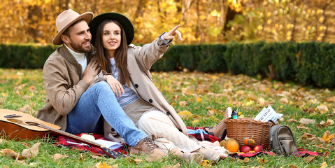 Happy young loving couple having picnic in beautiful autumn park