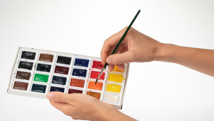 Watercolor paints and brush in women's hands gesture to dial paint on a brush