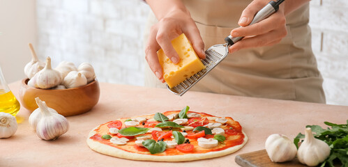 Obraz na płótnie Canvas Woman cooking tasty pizza in kitchen, closeup