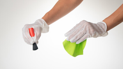 Hand gesture on a white background wearing protective gloves with a screen wipe cloth and dust brush