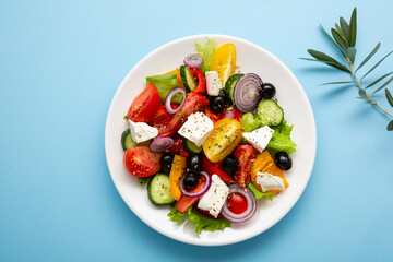 Top view of Fresh Greek salad o white plate mediterranean food on blue background