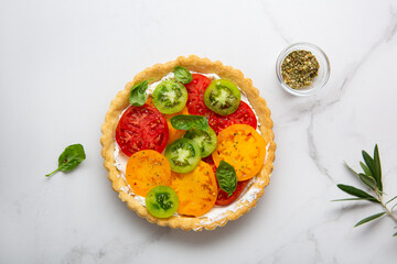 Overhead view of quiche with cheese and tomatoes on marble surface