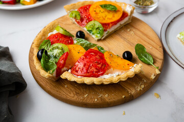 Close up of sliced quiche with cheese and tomatoes on kitchen board