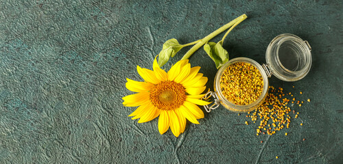 Jar of healthy bee pollen and sunflower on dark background with space for text