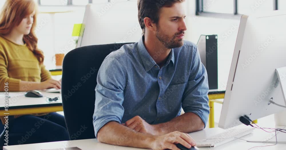 Poster Professional computer designer working on a new software technology design in his office desk. Serious, confident and young male web engineer coding with a female colleague in the background