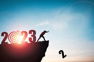 Silhouette man push number two from clip with 2023 year and blue sky for preparation new business target when change new year concept. - obrazy, fototapety, plakaty