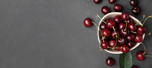 Bowl of tasty cherries on dark background with space for text, top view