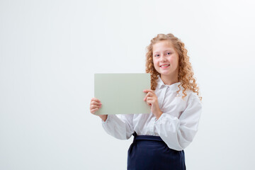 Fototapeta premium schoolgirl teen girl in school uniform holding a white sheet of paper , surprise on a white background